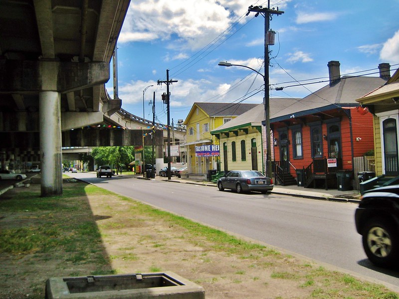 houses along a street are overwhelmed by a large elevated freeway structure