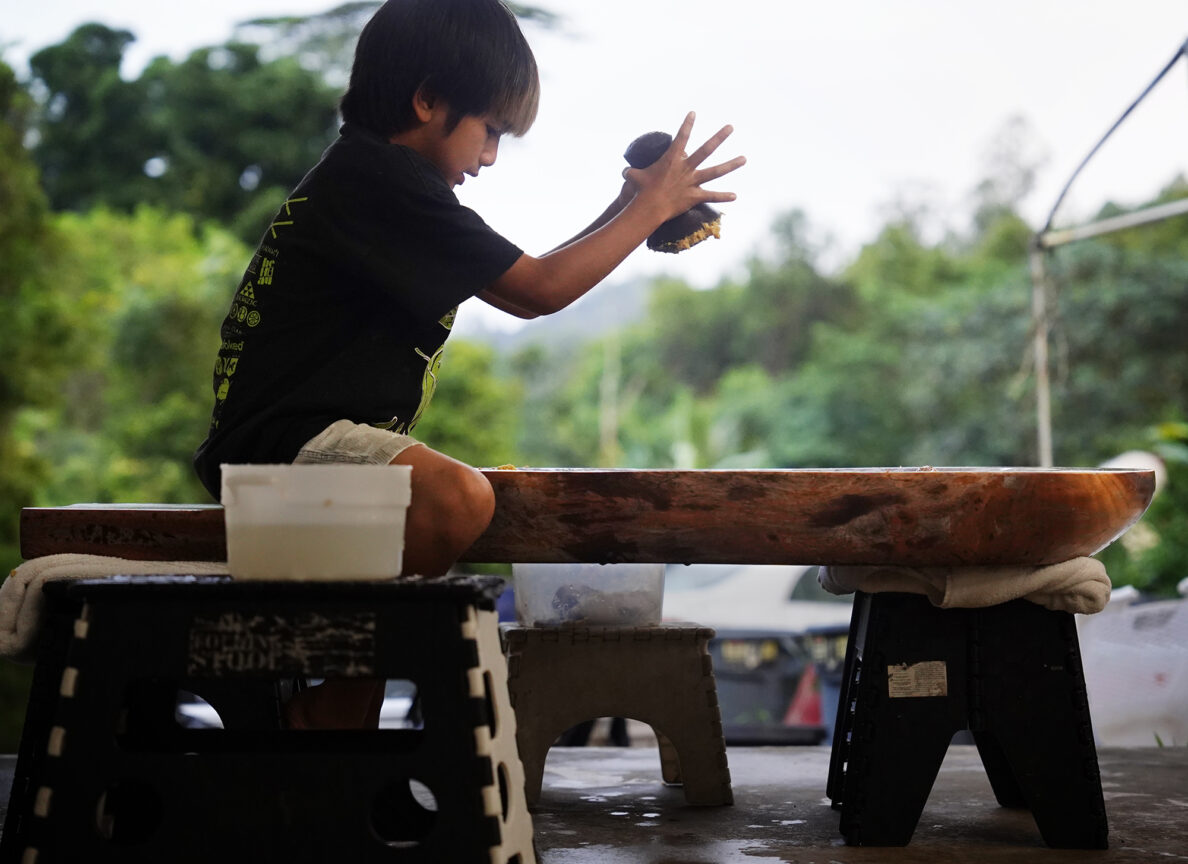 Daniel Anthony’s son Puea, 7, kui (pounds) kalo and ulu Thursday, Oct. 17, 2024, in Kaneohe. Daniel makes the pōhaku ku'i 'ai kui (stone for pounding food) and papa ku'i 'ai (pounding boards). (Kevin Fujii/Civil Beat/2024)