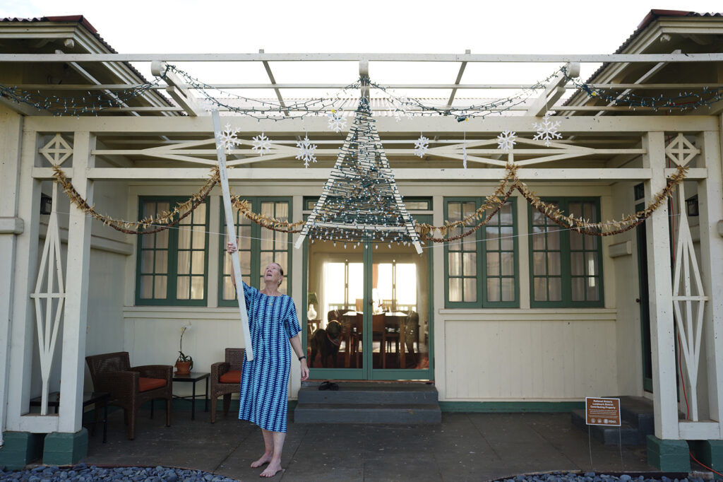 Dora Millikin untangles a Christmas decoration Thursday, Dec. 19, 2024, in Lahaina. The house made it through the Aug. 8, 2023, fire with very little damage. (Kevin Fujii/Civil Beat/2024)