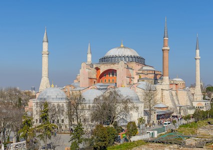 large square structure with multiple domes and columns topped. The building is capped by a large gold dome