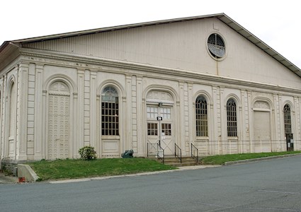 building facade showing four windows and one door. the building has a triangular roof