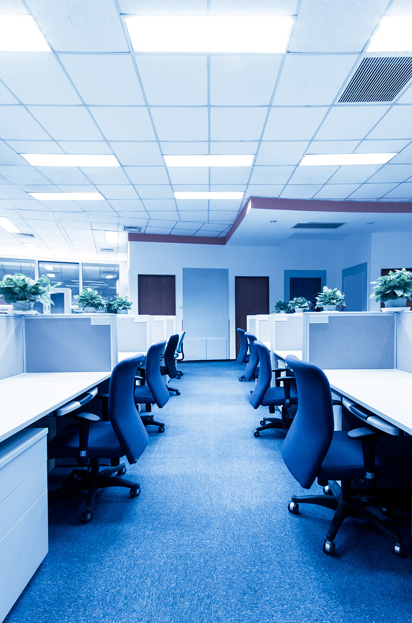 a row of blue office chairs in front of cubicles.