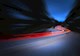 Cars leave curvy red trails on a road at night. 