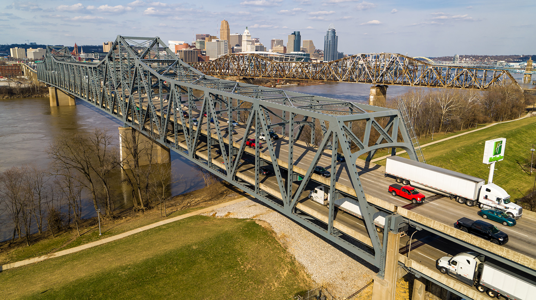 Double-decked steel bridge traverses a body of water. There are cars and trucks on both decks.