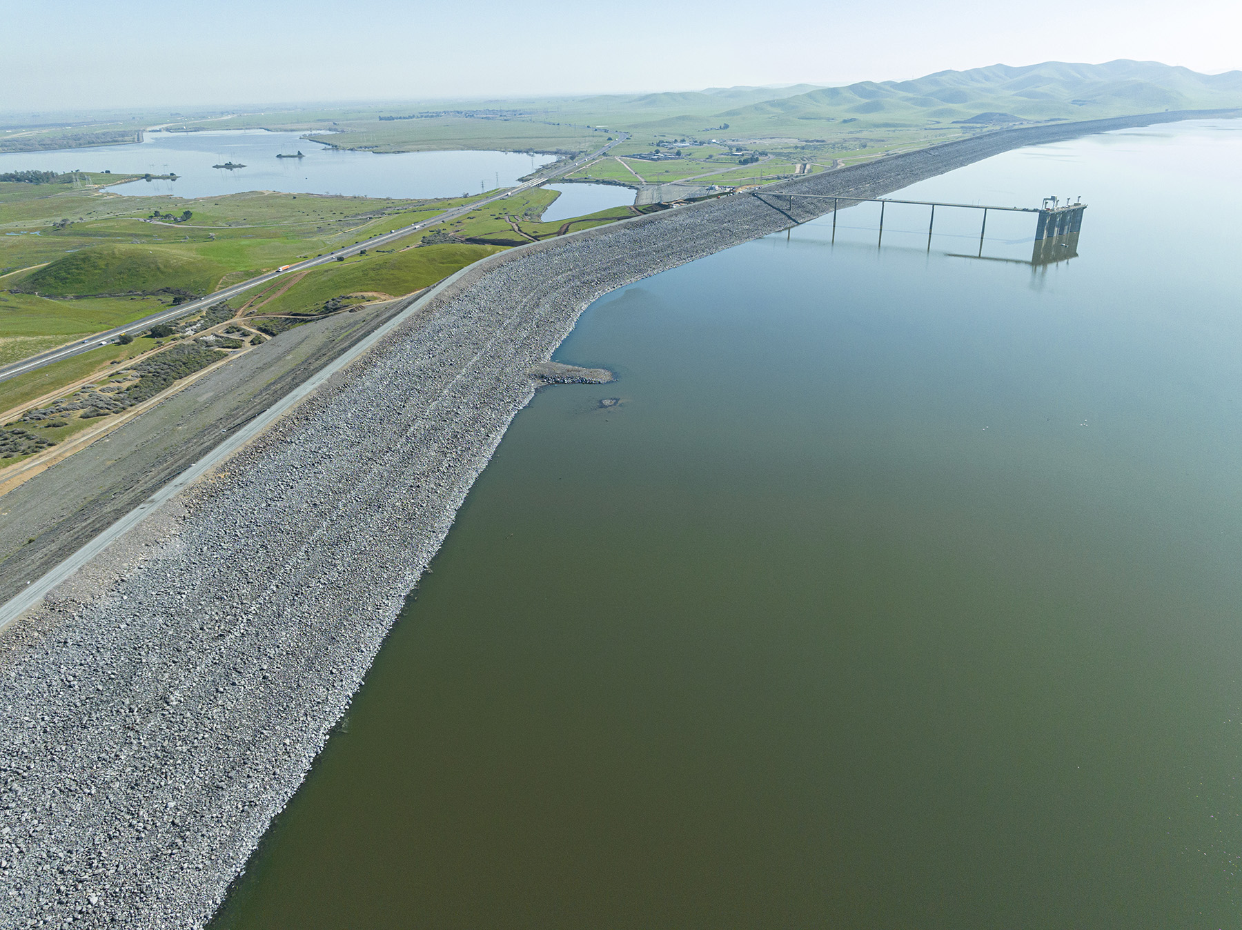 Image shows a dam with two large bodies of water separated by rocks and land.