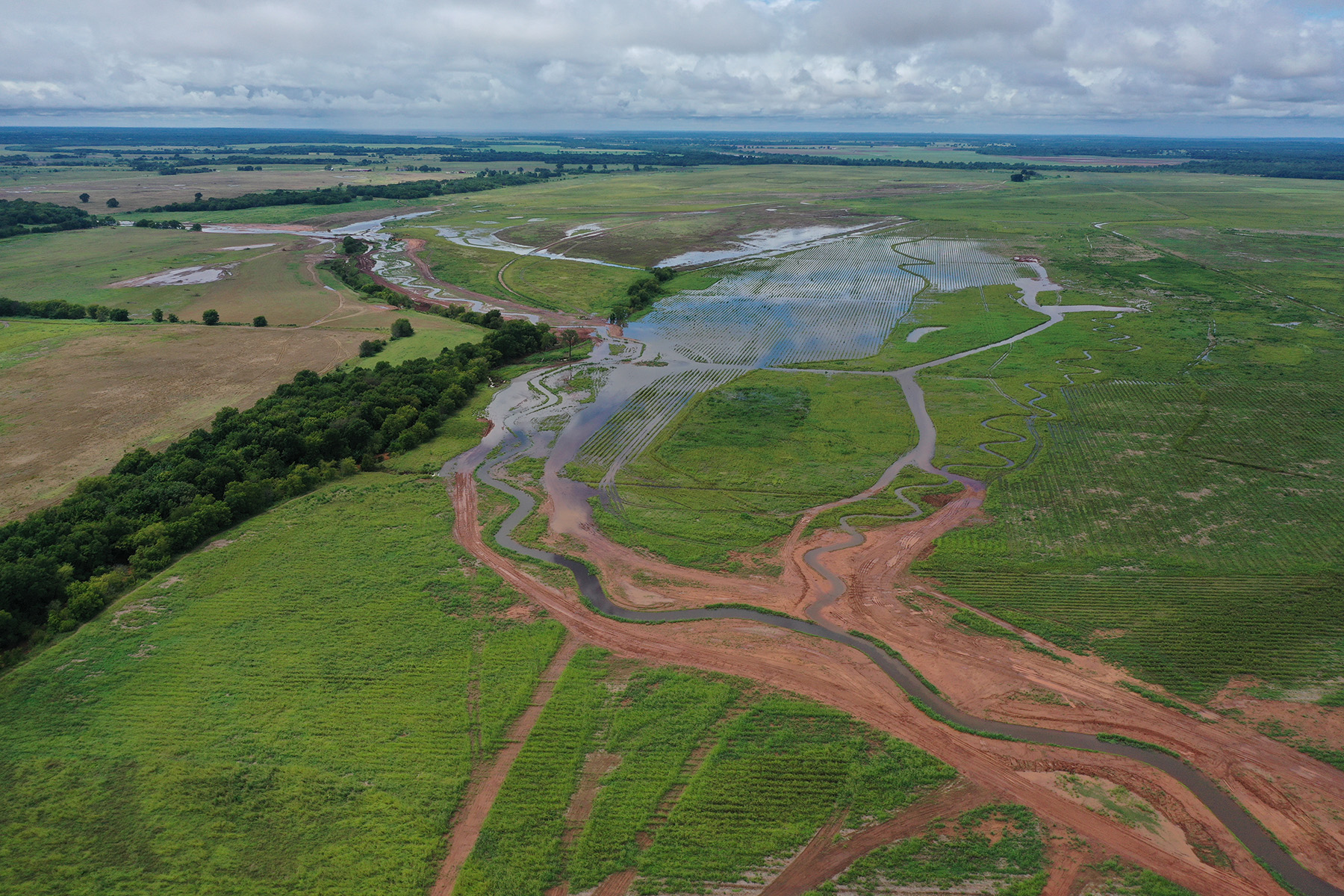 flooded creek and channel amidst green fields and trees