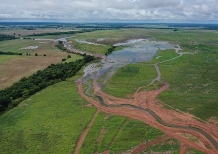 flooded creek and channel amidst green fields and trees