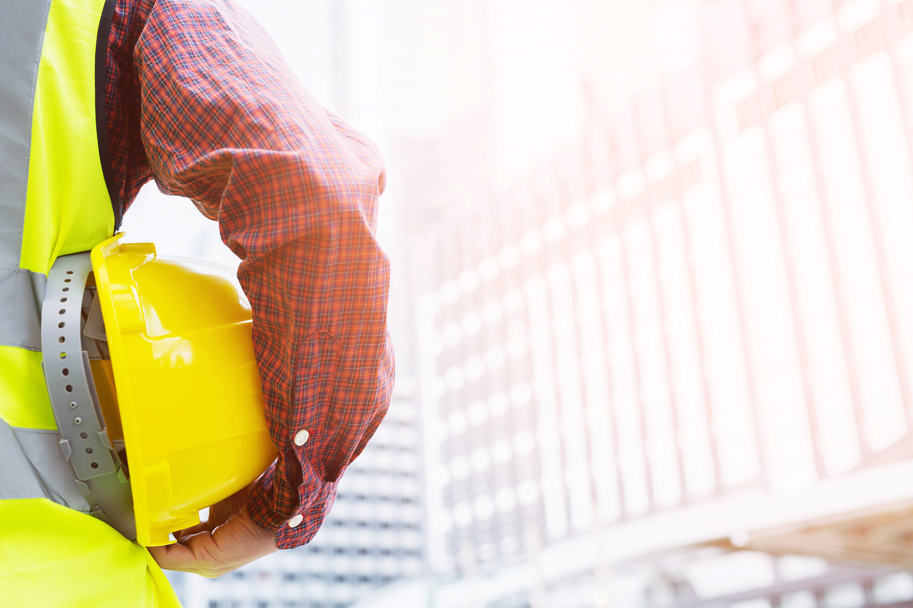 man holding yellow hard hat under his arm