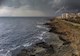 Ocean on the left, highway and buildings on the right depicting a coastal community. There is lightning in the background.