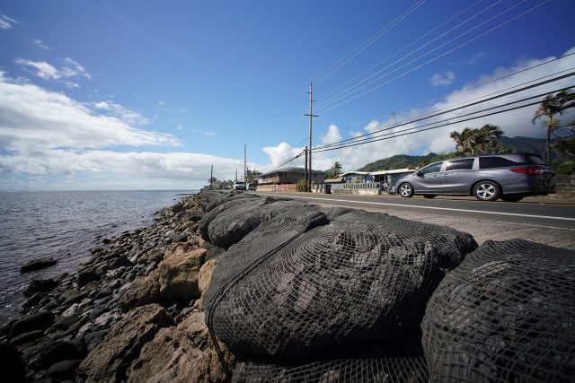 Large netted bags containing some black stone-like material along Kamehameha Highway in Hauula to protect the highway from rising tides.