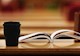 coffee mug on top of a table piled with books