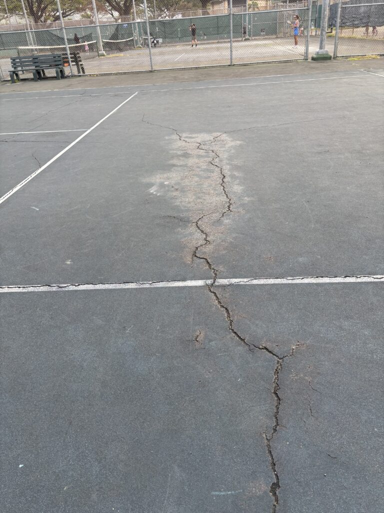 A crack in a tennis court at Mānoa Valley District Park.