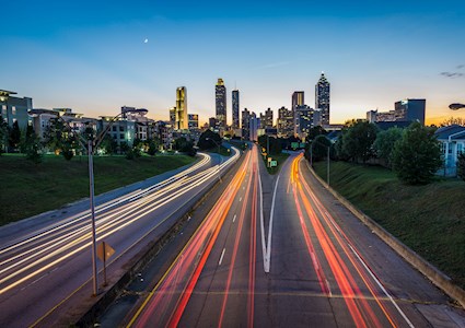 light trails on a highway heading to a city at dusk