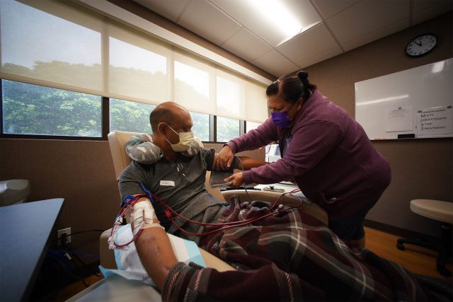 Kalani Pagan receives dialysis while Kalani's wife Kim Pagan adjusts the blood pressure device.