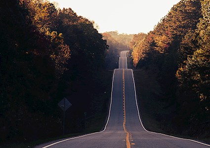 ROAD EXTENDS UP AND DOWN HILLS INTO THE DISTANCE